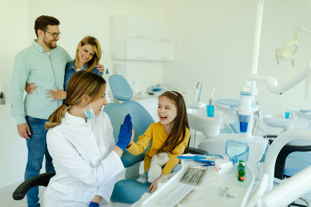 Dentist is giving hi five to little girl