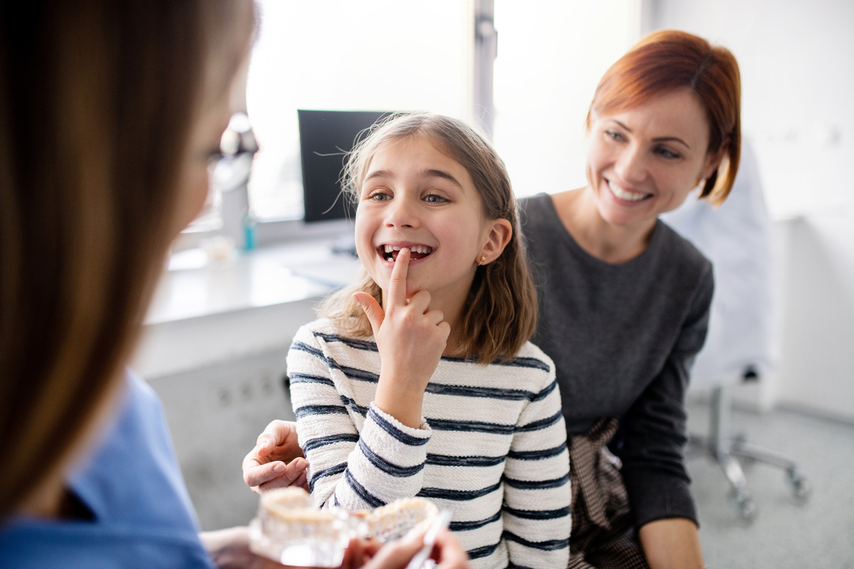 A small girl, mother and dentist in surgery, dental checkup.
