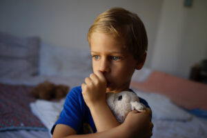 Vulnerable boy, insecure child, tired, holding soft toy, sucking thumb - at home