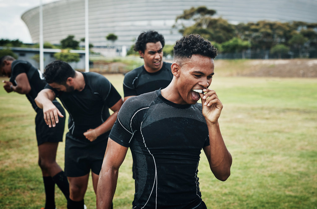 Cropped shot of a handsome young rugby player removing his mouthguard during half-time on the field.
