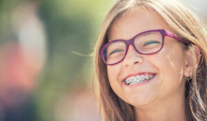 Smiling teenage girl with dental braces and glasses
