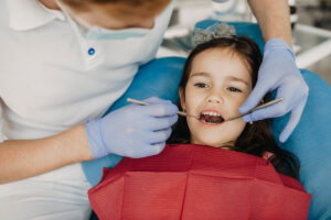 Lovely little girl sitting in stomatology seat having teeth examination by a pediatric dentist.