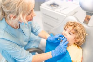 Pediatric dentist checking a young boy's teeth during a dental visit